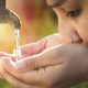 Young person drinking from an outdoor water faucet