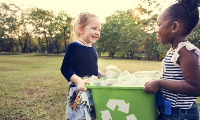 Photo of two young girls holding a recycling bin