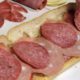Photo of a man making a submarine sandwich with mortadella, cooked salami, ham, Genoa salami and sweet capicola