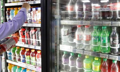 Photo of a shop owner reaching into a refrigerator