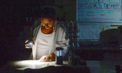 Photo of Carlos Lama using an LED lamp and his phone in his restaurant