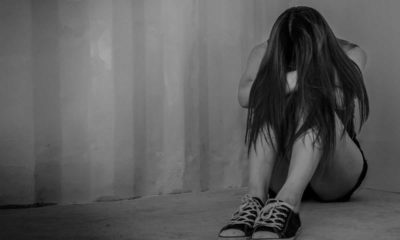 Photo of a sad young woman sitting in a room on the floor