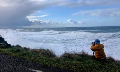 Photo of a man photographing waves crashing onto the cliffs at Rodea Point in Lincoln County, Ore.