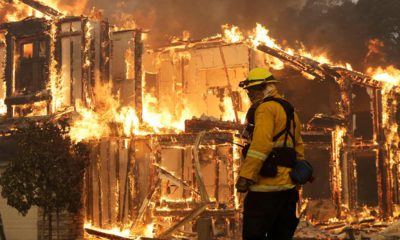 Photo of a firefighter monitoring a house burning in Santa Rosa, Calif.