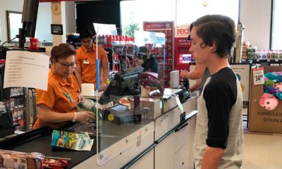 Photo of customer and grocery store cashier separated by a sneeze guard